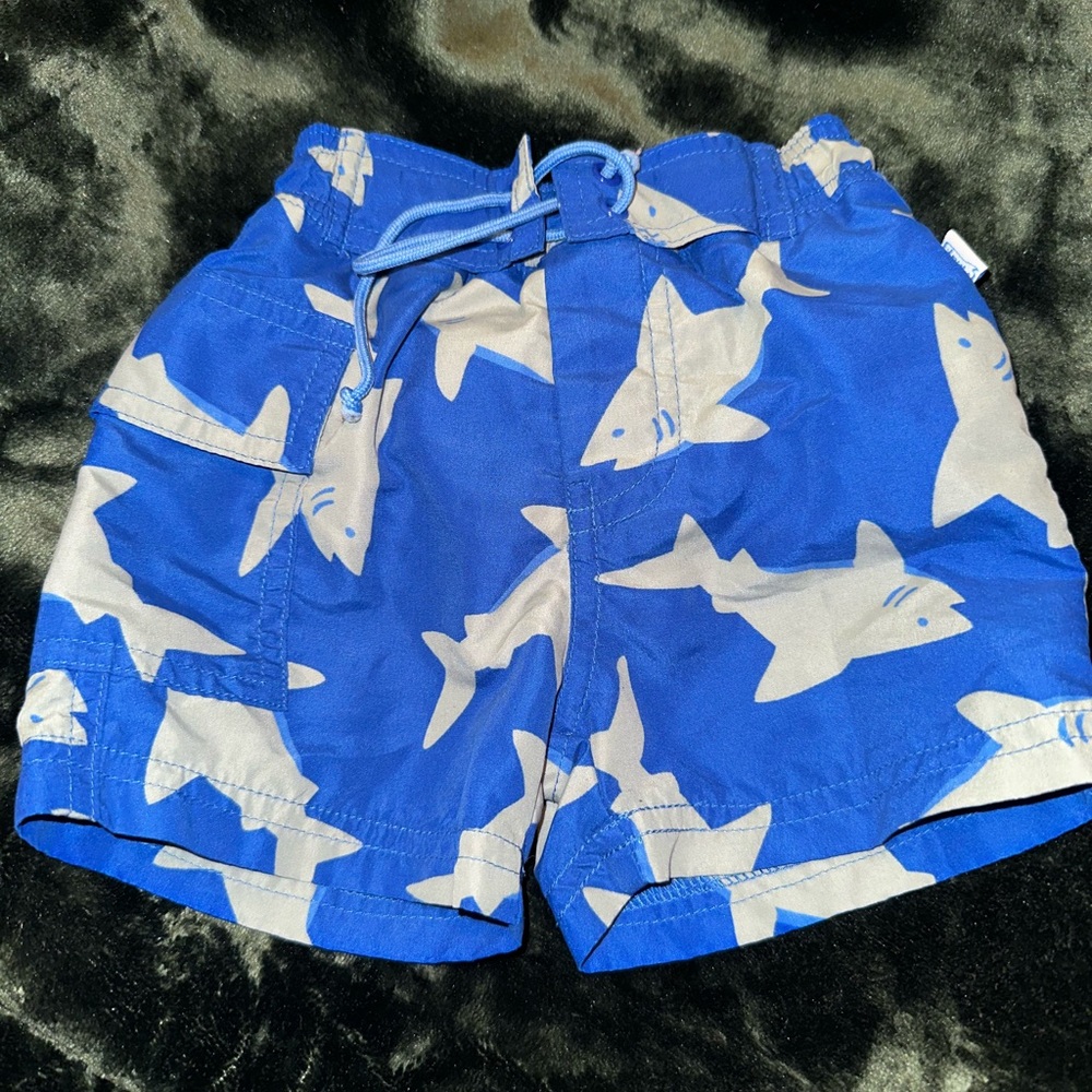I play blue and gray shark swim trunks 3-6 months
